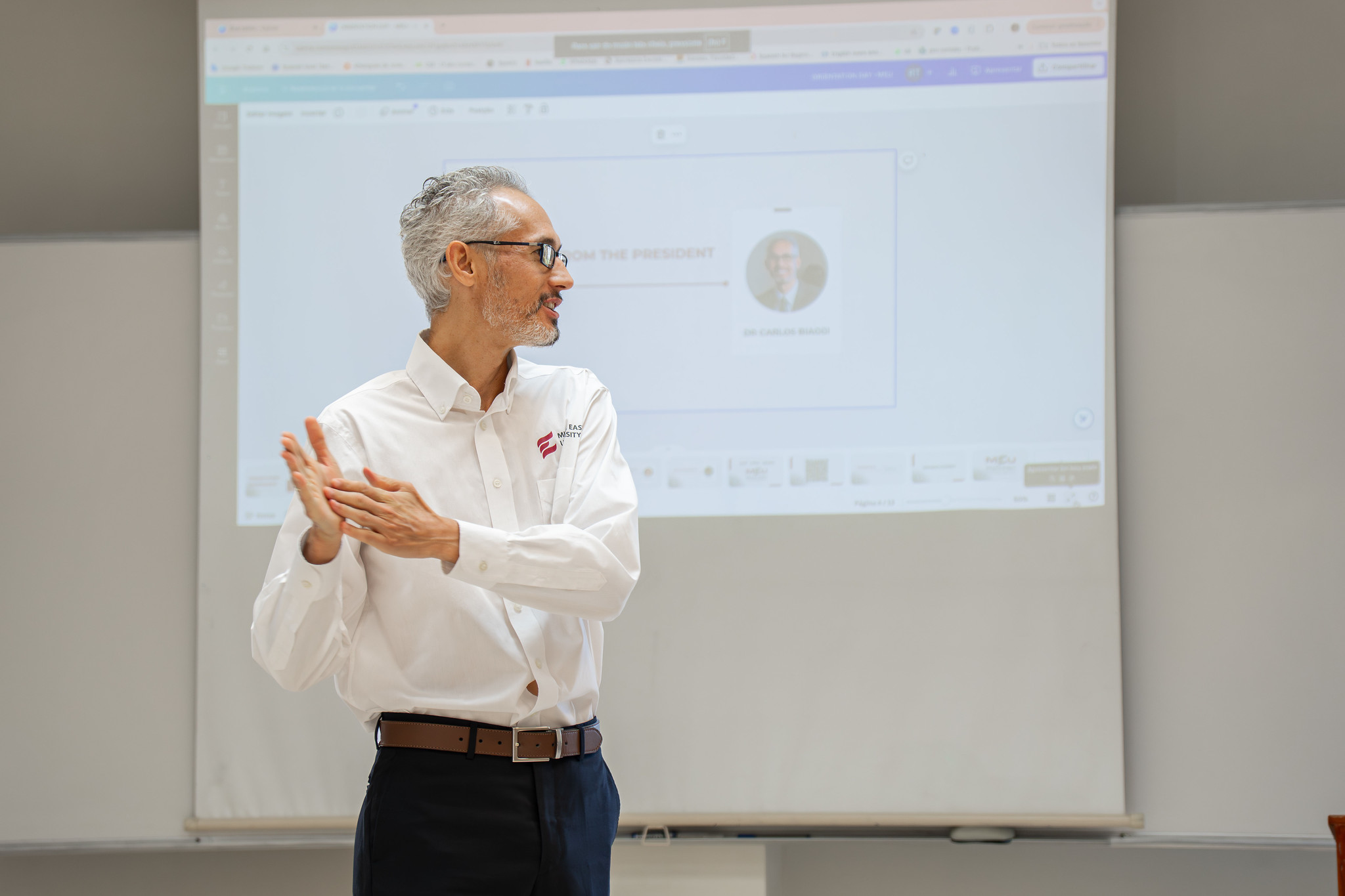 A speaker explaining ideas in front of a projected classroom presentation