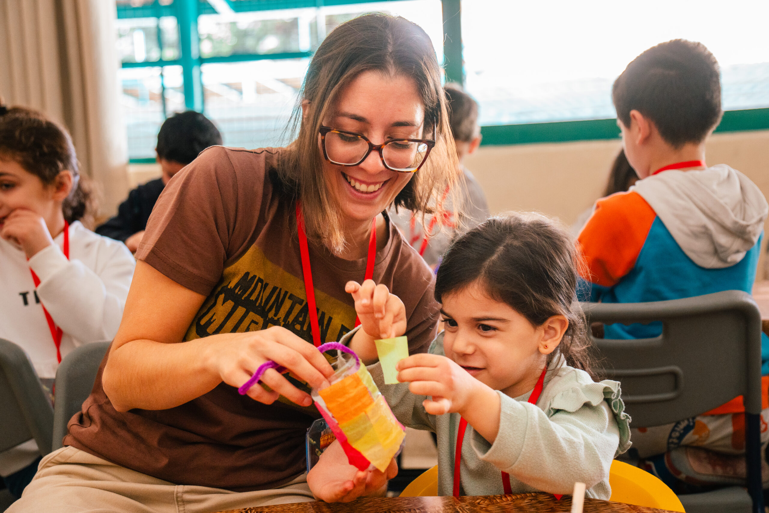 Smiling adult supporting a young child during a hands-on activity