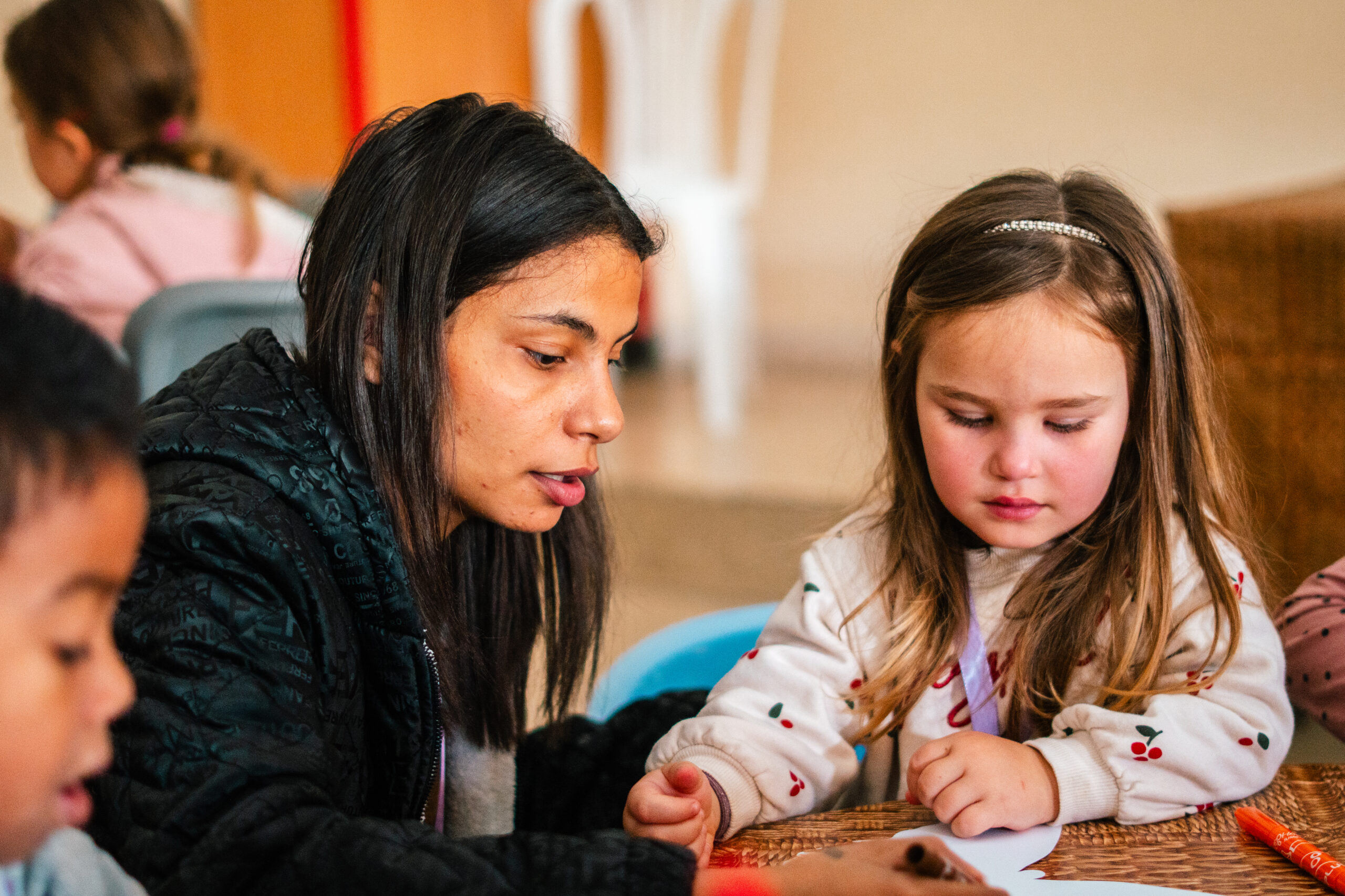 Young adult helping a child with a drawing and writing activity
