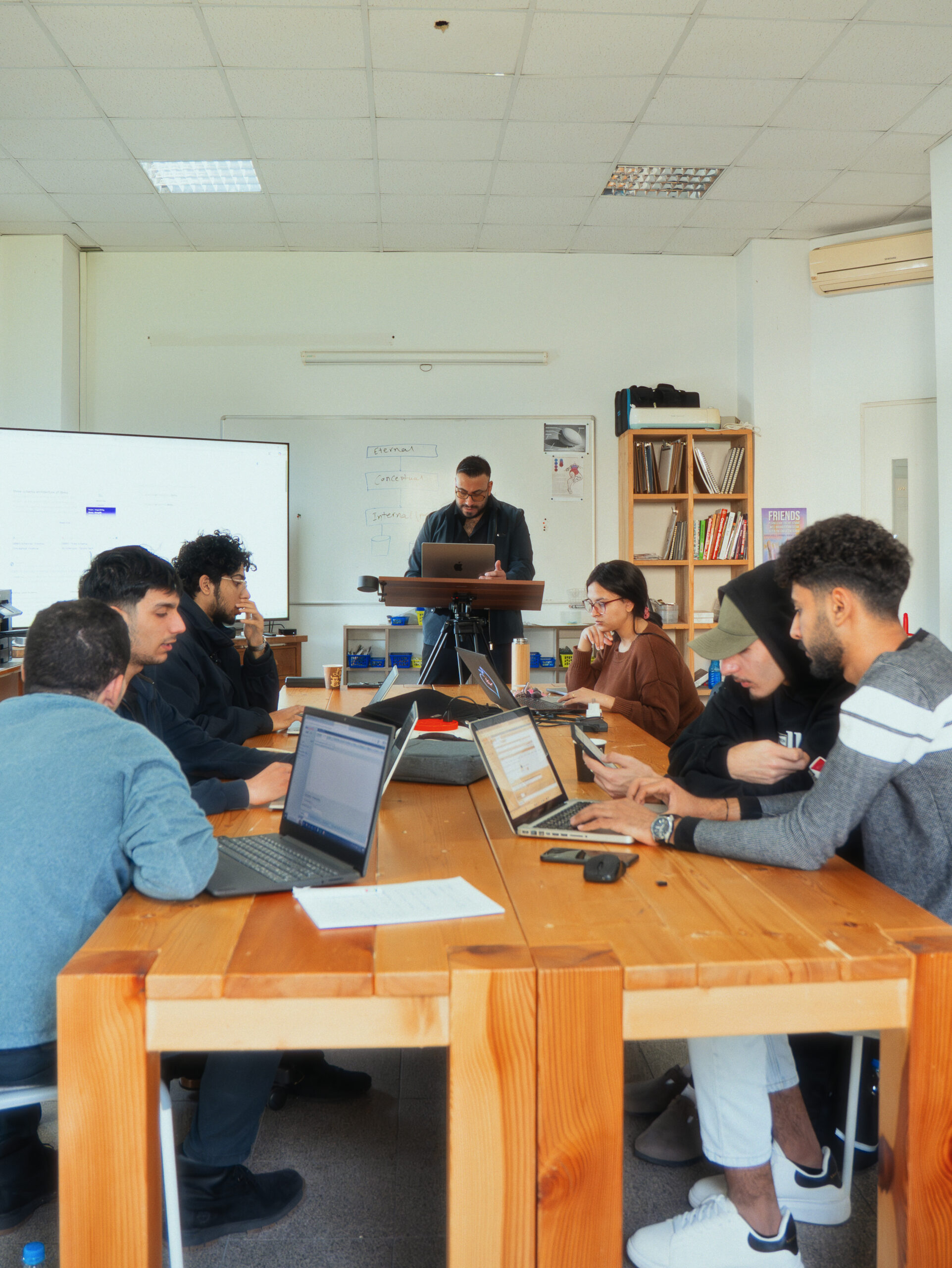Students working with laptops around a classroom table