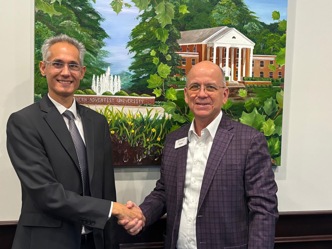 Two university representatives shaking hands during the partnership meeting