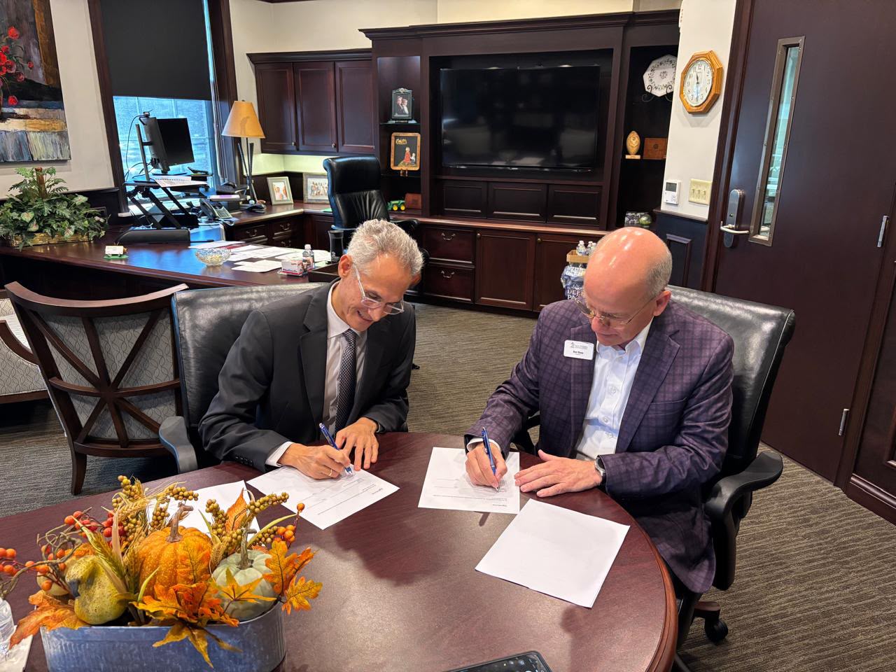 University representatives signing documents at a table