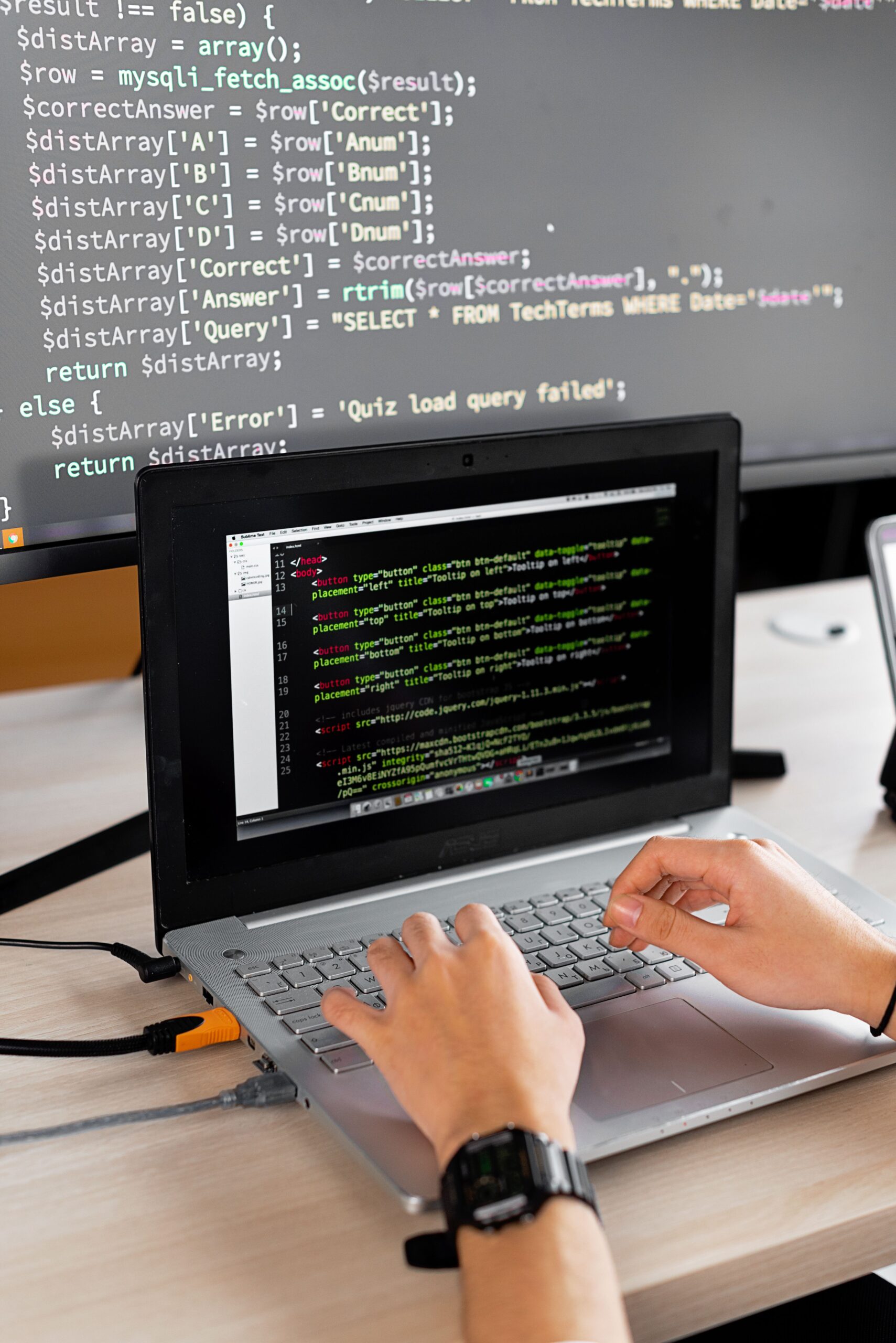 Person working on software development with a laptop and external monitor